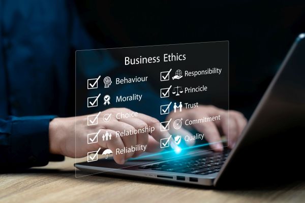 Person tippt auf Laptop mit eingeblendeten Begriffen wie Verantwortung Vertrauen Moral und Qualität als Werte ethischer Unternehmensführung.