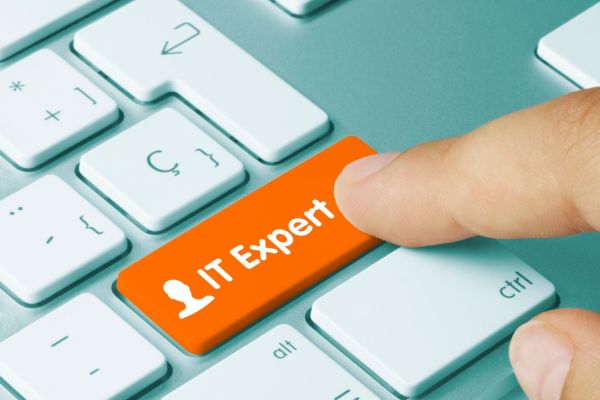 Finger drückt auf Tastatur, auf orage farbene Taste mit der Aufschrift "IT Expert"