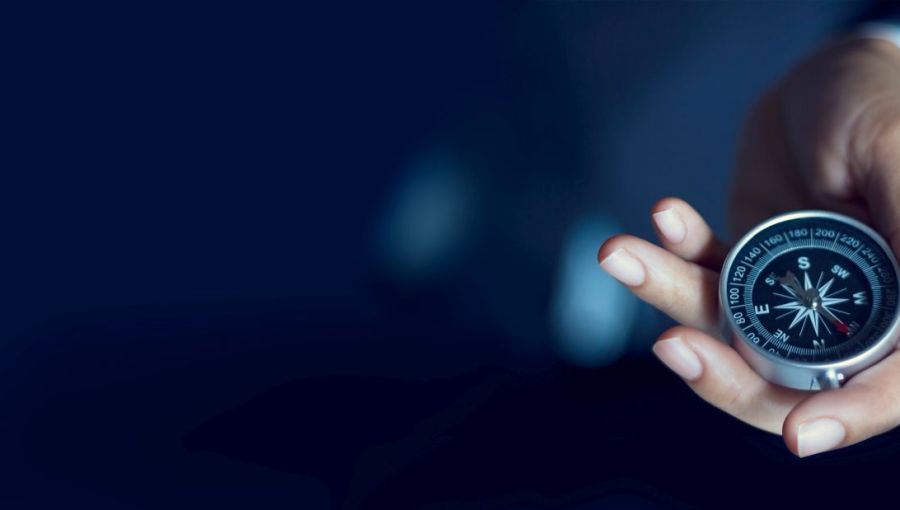 Eine Person in Anzug hält einen Kompass in ihrer Hand. 