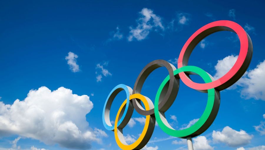 Große olympische Ringe vor blauem Himmel mit weißen Wolken: Symbol für internationale Zusammenarbeit und Projektmanagement bei den Olympischen Spielen.